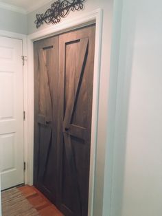 two wooden doors in a room with white walls and wood flooring on the side