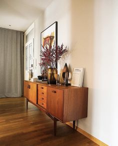 a wooden dresser sitting on top of a hard wood floor next to a white wall