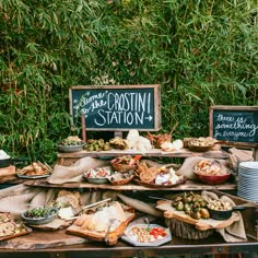 a table filled with lots of food on top of wooden trays next to green plants