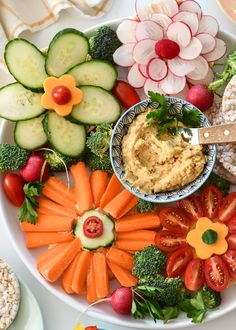 a white plate topped with lots of veggies and dip