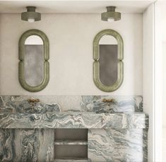 two mirrors on the wall above a marble sink