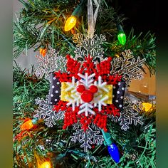 a christmas ornament hanging from the top of a tree with lights on it