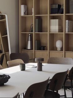 a table with several chairs around it in front of bookshelves