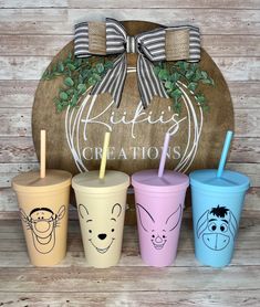 three different colored cups with straws in front of a sign that says kitty's creations