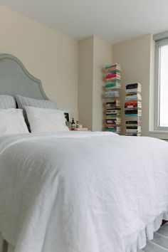 a bedroom with a bed, bookshelf and window in the corner next to it