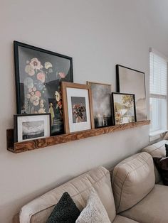 a living room filled with furniture and framed pictures on the wall above it's couch