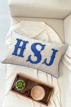 a pillow with the letters hsu on it sitting next to a wooden box and potted plant