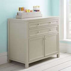 a white cabinet with some colorful toothbrushes on it's top in a blue room