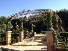 an outdoor patio with stone steps and trellis around the perimeter, surrounded by greenery