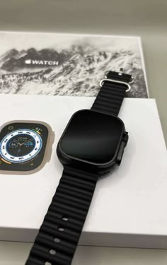 an apple watch sitting on top of a white box next to a black and silver strap