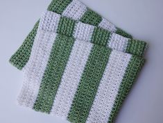 two green and white crocheted dishcloths sitting next to each other