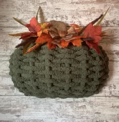 a crocheted pumpkin with leaves on it's top and bottom, sitting on a wooden surface