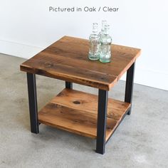 a wooden table with two glass bottles on top and one shelf below it that is made out of wood