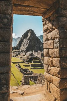 an open doorway leading to the ruins of machu picchuta in peru, with mountains in the background