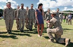 a woman in a blue and white dress is kneeling next to soldiers on the grass