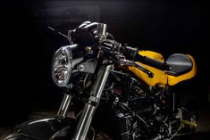 a yellow and black motorcycle parked in a dark room with lights on it's side