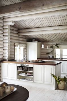 an open kitchen with white cabinets and wood flooring in a log cabin style home