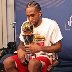 a man sitting in a chair holding a basketball trophy