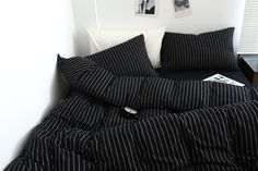 a bed with black and white striped comforter on top of it next to a window