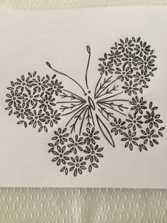 a black and white drawing of a butterfly with flowers on it's wings, sitting on top of a piece of paper