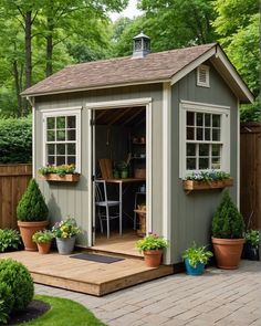 a small garden shed with potted plants on the deck and an outdoor kitchen in the back