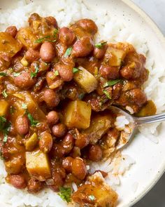 a white bowl filled with rice and beans on top of a table next to a fork