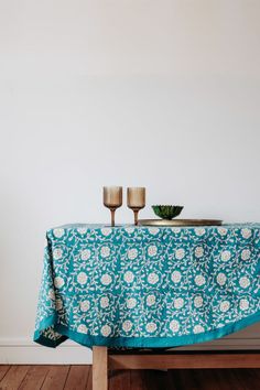 two candles are sitting on top of a table covered with a blue floral print cloth