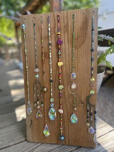 a wooden board with many different necklaces hanging from it's sides on a table