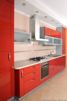 a kitchen with red cabinets and stainless steel appliances