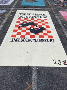 a street sign painted on the side of a road that says treat people with kindness including yourself