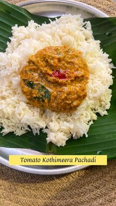 a white plate topped with rice and sauce on top of a leafy green surface