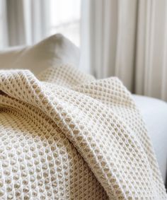 a white blanket sitting on top of a bed next to a window