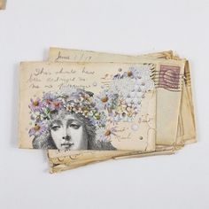 an old postcard with flowers on it is laying next to some envelopes that have writing on them