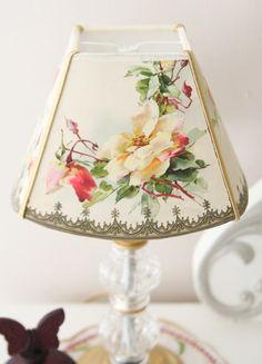 a lamp that is on top of a table with a flowered shade over it