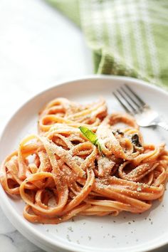 a white plate topped with pasta covered in sauce