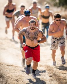 a group of men running down a dirt road