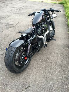 a black motorcycle parked on top of a parking lot next to a grass covered field