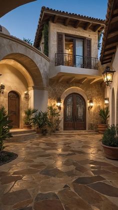 the entrance to a large home with stone floors and arched doorways, surrounded by potted plants