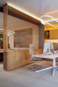 an office with two desks and chairs in front of a wooden screen divider