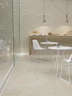 a white table and two chairs in a room with glass walls on both sides, next to a counter