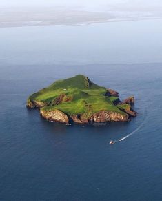 an island in the middle of the ocean with a boat on it's side