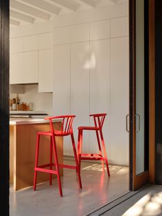 two red chairs sitting next to each other in a kitchen