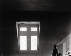 black and white photograph of a woman sitting in front of a window