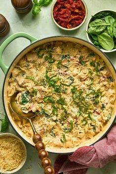 a large pot filled with pasta and sauce next to other bowls full of vegetables on a table