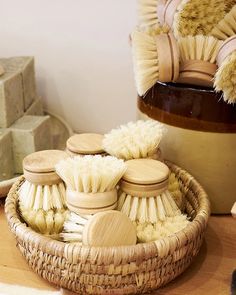 several brushes are arranged in a basket on a table next to soaps and sponges