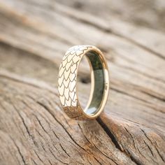 a gold wedding ring sitting on top of a piece of wood