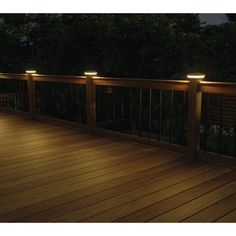 an outdoor deck with lights on it and trees in the background, at night time