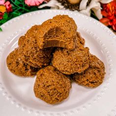 a white plate topped with cookies on top of a table covered in flowers and greenery