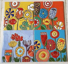 four different pictures of flowers painted on tile