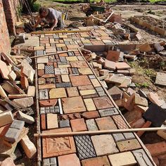 a man laying bricks on the ground next to a building